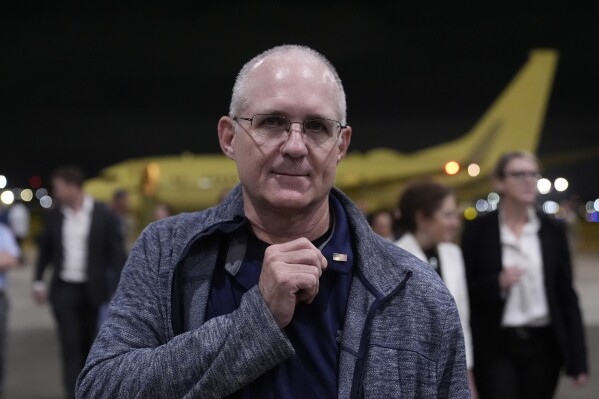 Paul Whelan shows a pin he received from President Joe Biden as he arrives at Kelly Field after being released by Russia, Friday, Aug. 2, 2024, in San Antonio. (AP Photo/Eric Gay)