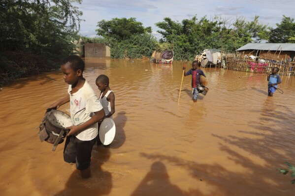 FILE - Children flee flood waters that wreaked havoc in Mororo, on the border of Tana River and Garissa counties in northeastern Kenya, April 28, 2024. The impact of the devastating rains that hit East Africa from March to May intensified from a mix of climate change and rapid urban growth, an international team of climate scientists said in a study.  (AP Photo/Andrew Kasuku, File)
