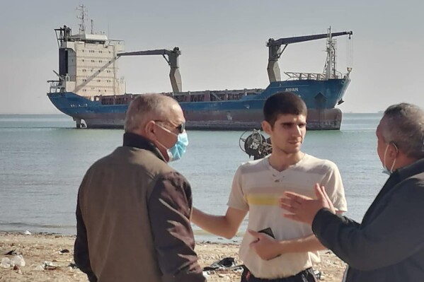 This photo provided by the International Transport Workers’ Federation shows Mohammad Aisha, center, near the abandoned cargo ship MV Aman in Egyptian waters in March 2021. (ITF via AP)