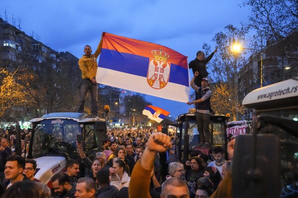 People hold a Serbian flag during a protest, day after the assault on students was carried out by thugs with baseball bats, in Novi Sad, Serbia, Tuesday, Jan. 28, 2025. (AP Photo/Darko Vojinovic)