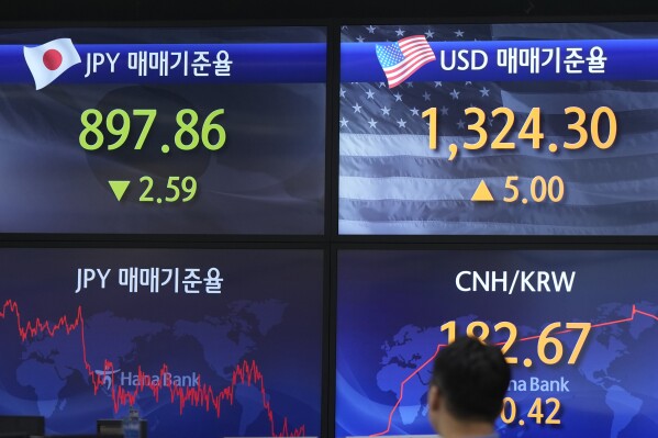 A currency trader walks by the screens showing the foreign exchange rates at a foreign exchange dealing room in Seoul, South Korea, Wednesday, Sept. 6, 2023. (AP Photo/Lee Jin-man)