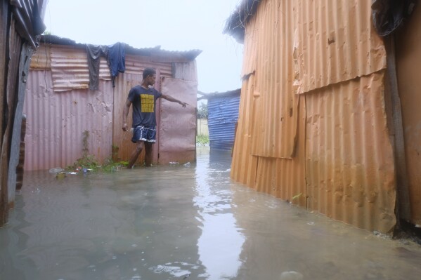 A man walks between houses flooded by the rains of Tropical Storm Franklin, along the Ozama River in the Gualey neighborhood of Santo Domingo, Dominican Republic, Wednesday, Aug. 23, 2023. (AP Photo/Ricardo Hernandez)