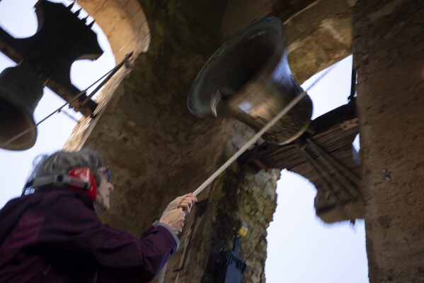 Roser Reixach, a student of the Vall d'en Bas School of Bell Ringers, performs playing a bronze bell at the church bell tower of the12th-century Sant Romà church, at the tiny village of Joanetes, about two hours north of Barcelona, Spain, Saturday, June 29, 2024. A school set up to revive the manual ringing of church bells has graduated its first class of 18 students after learning their ringing skills. (AP Photo/Emilio Morenatti)