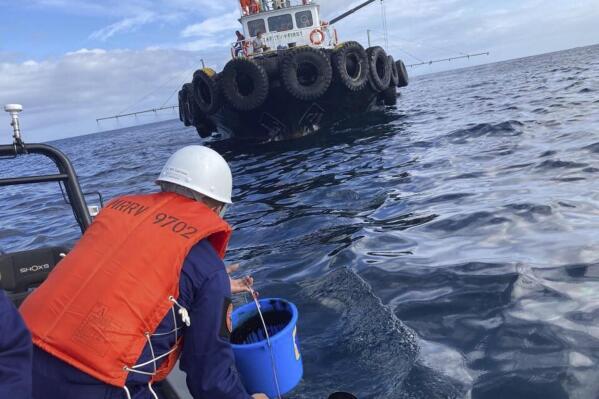 In this handout photo provided by the Philippine Coast Guard, a coast guard personnel collects water samples from an oil spill in the waters off Naujan, Oriental Mindoro, central Philippines, Thursday March 2, 2023. Oil leaking from Philippine tanker MT Princess Empress that sank off a province southwest of the capital has prompted at least seven coastal towns to temporarily ban fishing and swimming, officials said Thursday. (Philippine Coast Guard via AP)