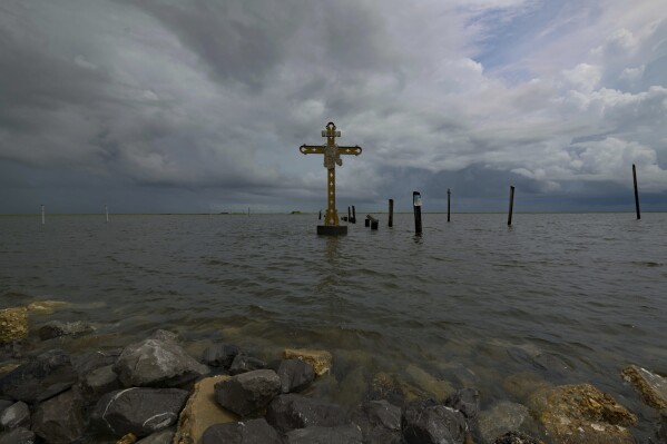 FILE - A cross erected on Shell Beach as a memorial to the residents in St. Bernard Parish, La. who died after Hurricane Katrina in 2005 is visible before Hurricane Ida makes landfall in New Orleans, Aug. 28, 2021. Hurricanes in the U.S. over last few decades killed thousands more people than meteorologists traditionally calculate and a disproportionate number of those victims are poor, vulnerable and minorities, according to a new epidemiological study released Wednesday, Aug. 16, 2023. (AP Photo/Matthew Hinton, File)