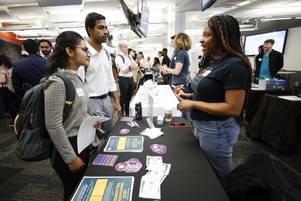 FILE -- Georgia State University students Kavita Javalagi, left, and Gana Natarajan, second from left, speak with Shetundra Pinkston, during the Startup Student Connection job fair, March 29, 2023, in Atlanta. Georgia officials are launching a program to encourage more high school seniors to apply to college, saying it will bolster incomes and educate more qualified workers. Gov. Kemp and others unveiled the new program, Thursday, Oct. 5, encouraging more young people to attend college. (AP Photo/Alex Slitz, file)