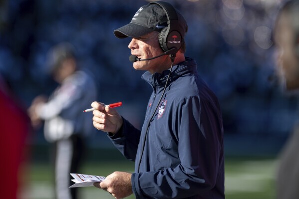 Connecticut head coach Jim Mora watches his team from their bench during the first half of an NCAA college football game against James Madison in Harrisonburg, Va., Saturday, Nov. 11, 2023. (Daniel Lin/Daily News-Record via AP)