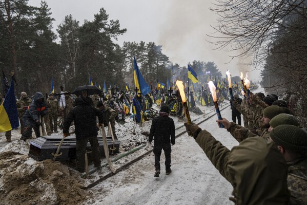 Funeral workers down a coffin into a grave during a funeral ceremony of Sviatoslav Romanchuk, Ukrainian serviceman, at the cemetery in Kyiv, Ukraine, Wednesday, Jan. 3, 2024. Romanchuk joined territorial defence since the beginning of or Russian invasion and was killed on Dec. 28, 2023 in Lyman direction, Donetsk region. (AP Photo/Evgeniy Maloletka)