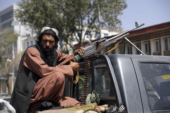 A Taliban fighter sits on the back of a vehicle with a machine gun in front of the main gate leading to the Afghan presidential palace, in Kabul, Afghanistan, Monday, Aug. 16, 2021. The U.S. military has taken over Afghanistan's airspace as it struggles to manage a chaotic evacuation after the Taliban rolled into the capital. (AP Photo/Rahmat Gul)
