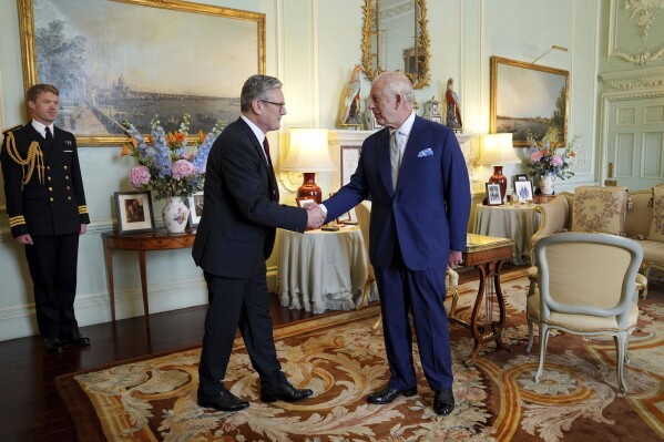 Britain's King Charles III, right, shakes hands with Keir Starmer where he invited the Labour Party leader to become prime minister and to form a new government, following the landslide general election victory for the Labour Party, in London, Friday, July 5, 2024. (Yui Mok, Pool Photo via AP)