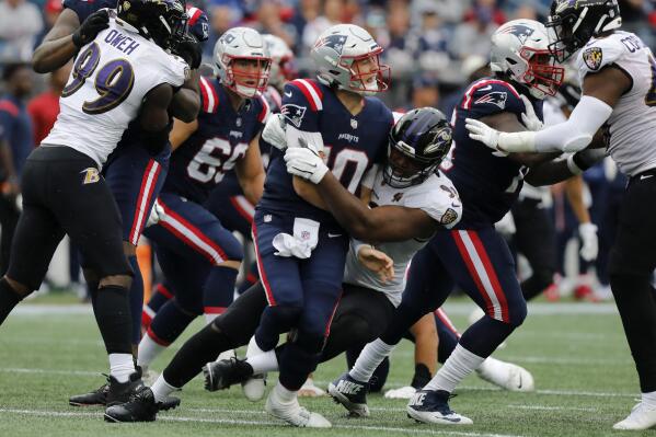 New England Patriots quarterback Mac Jones, center left, is brought down by Baltimore Ravens defensive tackle Calais Campbell, center, right, in the second half of an NFL football game, Sunday, Sept. 25, 2022, in Foxborough, Mass. Jones limped to the sidelines following the play. (AP Photo/Paul Connors)