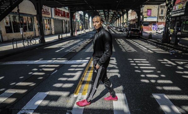 In this March 26, 2020, photo, Rahmell Peeples walks in his neighborhood during an interview in the Brooklyn borough of New York. Peebles, who is skeptical of what he hears from white-run media and government, didn’t see the need for alarm over the new coronavirus. Peebles is one of roughly 40 million black Americans deciding minute by minute whether to put their faith in the government and medicine during the coronavirus pandemic. “I’ve just been conditioned not to trust,” Peebles said. (AP Photo/Bebeto Matthews)