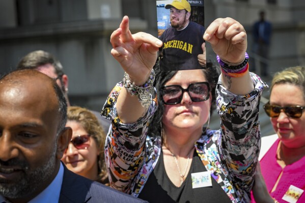 Shannon Reynolds holds up a photo of her brother Timothy Reynolds after a 15-year-old squeegee worker was found guilty of manslaughter for killing Reynolds at Conway and Light Streets last year, in Baltimore, Thursday, July 27, 2023. (Jerry Jackson/The Baltimore Sun via AP)