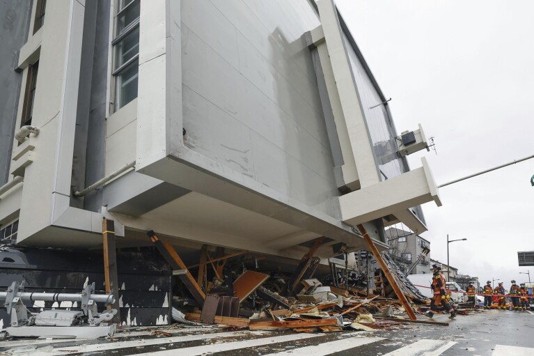 Firefighters search a fallen building hit by earthquakes in Wajima, Ishikawa prefecture, Japan Wednesday, Jan. 3, 2024. (Kyodo News via AP)