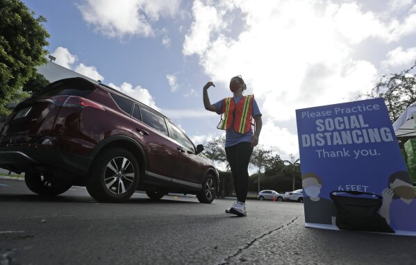 Shayna Weiss directs drivers at a kosher food drive-thru distribution site, Wednesday, July 29, 2020, at the Greater Miami Jewish Federation building in Miami. (AP Photo/Wilfredo Lee)