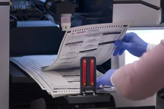FILE - An election worker removes tabulated ballots from the machine inside the Maricopa County Recorders Office, Thursday, Nov. 10, 2022, in Phoenix. The Associated Press on Wednesday, May 31, 2023 reported on false claims circulating on social media that newly released video shows election officials in Maricopa County, Arizona illegally conducting “secret" voting equipment tests ahead of last November’s contested midterms. (AP Photo/Matt York, File)