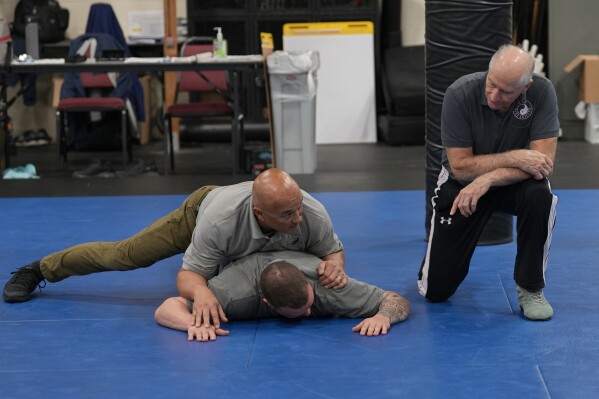 Instructor Dave Rose, right, watches as fellow instructor Enrico Solomon, top, demonstrates the basics of ground control on a student during an Arrest & Control Instructor course in Sacramento, Calif., on Thursday, Jan.18, 2024. (AP Photo/Rich Pedroncelli)