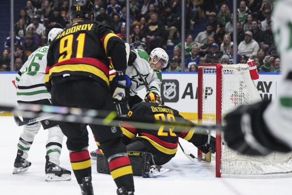 Dallas Stars' Roope Hintz, back center, scores against Vancouver Canucks goalie Casey DeSmith during the first period of an NHL hockey game Thursday, March 28, 2024, in Vancouver, British Columbia. (Darryl Dyck/The Canadian Press via AP)