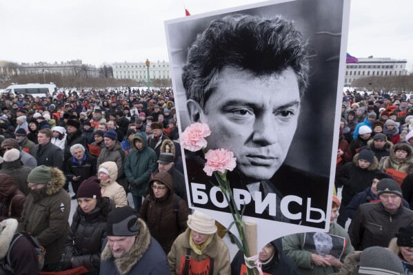 FILE - In this Sunday, Feb. 26, 2017 file photo, People gather in memory of opposition leader Boris Nemtsov, portrait in center, in St. Petersburg, Russia. Once deputy prime minister under Boris Yeltsin, Nemtsov was a popular politician and harsh critic of Putin. On a cold February night in 2015, he was gunned down by assailants on a bridge adjacent to the Kremlin as he walked with his girlfriend in a death that sent shockwaves across the country. (AP Photo/Dmitri Lovetsky, file)