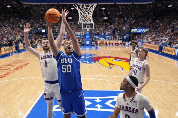 El centro de BYU, Aly Khalifa (50), dispara durante la segunda mitad de un partido de baloncesto universitario de la NCAA contra Kansas el martes 27 de febrero de 2024 en Lawrence, Kansas. BYU ganó 76-68.  (Foto AP/Charlie Riedel)