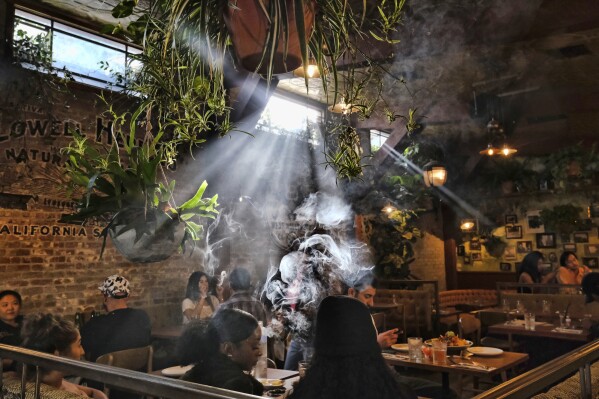 FILE - Patrons smoke marijuana at Lowell's Original Cannabis Cafe, a legal marijuana establishment, in Los Angeles, Nov. 13, 2019. (AP Photo/Richard Vogel, File)