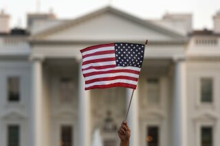 FILE - In this Sept. 2017 file photo, a flag is waved during an immigration rally outside the White House, in Washington.  The Trump administration says it'll allow migrants from six countries to extend their legal U.S. residency under a temporary status for nine months while courts consider its effort to end the program. President Donald Trump has long sought to terminate the program, which allows migrants from countries devastated by war or natural disaster to legally live in the U.S. President-elect Joe Biden has promised “an immediate review" of it and said he’ll pursue legislation for longtime residents to remain and seek U.S. citizenship. The Department of Homeland Security announced the extension Wednesday.  (AP Photo/Carolyn Kaster)