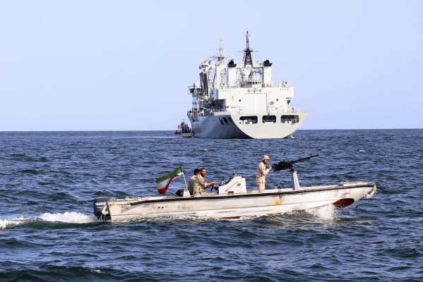 In this photo provided Tuesday, March 12, 2024, by the Iranian Army, an Iranian military boat patrols as a warship enters the Iranian waters prior to start of a joint naval drill of Iran, Russia and China in the Indian Ocean. Iran has stepped up its military cooperation with Beijing and Moscow in response to regional tensions with the United States, including by supplying military drones to Russia before the European nation invaded Ukraine in 2022. (Iranian Army via AP)