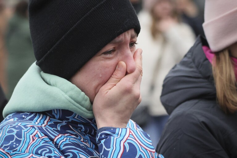 A woman reacts as she comes to place flowers at the fence next to the Crocus City Hall, on the western edge of Moscow, Russia, Sunday, March 24, 2024. The suburban Moscow concert hall where gunmen opened fire on concertgoers was a blackened, smoldering ruin as the death toll in the attack surpassed 130 and Russian authorities arrested four suspects. (AP Photo/Vitaly Smolnikov)