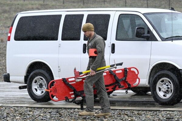 A U.S. Marine carries rescue gear at a command center Wednesday, Feb. 7, 2024, in Kitchen Creek, Calif. A Marine Corps helicopter that had been missing with five troops aboard as an historic storm continued drenching California was found Wednesday morning in a mountainous area outside San Diego. (AP Photo/Denis Poroy)