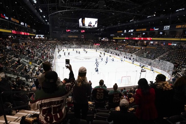 FILE - Fans watch as players warm up prior to the Arizona Coyotes' home-opening NHL hockey game against the Winnipeg Jets at the 5,000-seat Mullett Arena in Tempe, Ariz., Oct. 28, 2022. The Coyotes say owner Alex Meruelo has executed a letter of intent to buy a piece of land for a potential arena in Mesa, Arizona. The move comes months after voters in Tempe rejected a referendum to construct an arena there for the NHL club. (AP Photo/Ross D. Franklin, File)