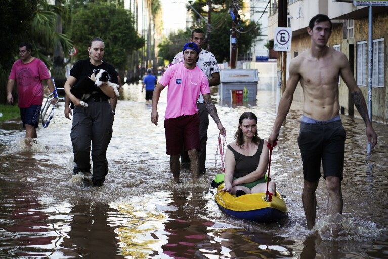 PLIK – Kobieta została uratowana z obszaru zalanego przez ulewne deszcze w Porto Alegre, stan Rio Grande do Sul, Brazylia, poniedziałek, 6 maja 2024 r.  W świecie, który w ostatnich dniach i tygodniach coraz bardziej przyzwyczaja się do gwałtownych wahań pogody, wydaje się, że te ekstrema środowiskowe osiągnęły nowy poziom.  (AP Photo/Carlos Macedo, plik)