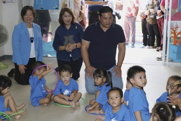 In this photo provided by the Foundation For Slum Child Care, Vacharaesorn Vivacharawongse, center right, visits the daycare center in Bangkok, Thailand, Tuesday, Aug. 8, 2023. The estranged son of Thailand’s King Maha Vajiralongkorn visited the daycare center for underprivileged children in Bangkok on Tuesday following his surprise return to the country after 27 years of living abroad. (Foundation For Slum Child Care via AP)