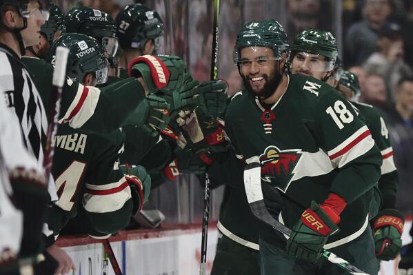 Minnesota Wild left wing Jordan Greenway (18) smiles while greeting teammates after scoring his first goal of the season, against the Arizona Coyotes during the second period of an NHL hockey game Tuesday, Nov. 30, 2021, in St. Paul, Minn. (AP Photo/Stacy Bengs)