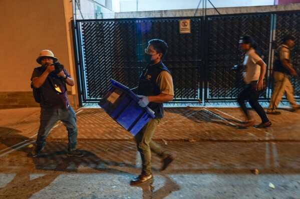 An agent from the Attorney General's office carries evidence collected at Save the Children's headquarters during a raid, in Guatemala City, Thursday, April 25, 2024. The NGO is being investigated for an alleged complaint about the violation of migrant children's rights, according to statements made by prosecutor Rafel Curruchiche. (AP Photo/Moises Castillo)