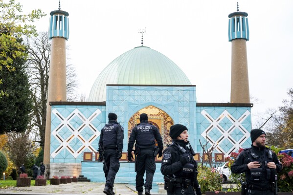 Police officers stand in front of the Imam Ali Mosque (Blue Mosque) on the Outer Alster, during a raid, in Hamburg, Germany, Thursday, Nov. 16, 2023. The German government says police have raided 54 properties across the country in an investigation of a Hamburg-based center suspected of promoting Iranian ideology and supporting activities of Hezbollah. The Interior Ministry said that Wednesday the Islamic Center Hamburg has long been under observation by Germany’s domestic intelligence agency. (Daniel Bockwoldt/dpa via AP)