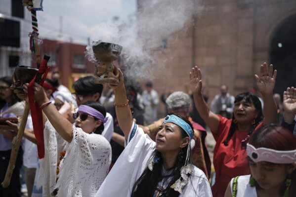 Claudia Santos performs a ceremony with residents and members of an Amaxac Indigenous organization to commemorate the 503rd anniversary of the fall of the Aztec empire's capital, Tenochtitlan, in Mexico City, Tuesday, Aug. 13, 2024. (AP Photo/Eduardo Verdugo)