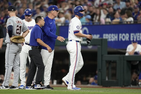 Texas Rangers' Corey Seager, right, is followed off the field by manager Bruce Bochy and trainer Mat Lucero, center left, after Seager hit an RBI single against the Detroit Tigers in the second inning of a baseball game, Wednesday, June 5, 2024, in Arlington, Texas. (AP Photo/Tony Gutierrez)