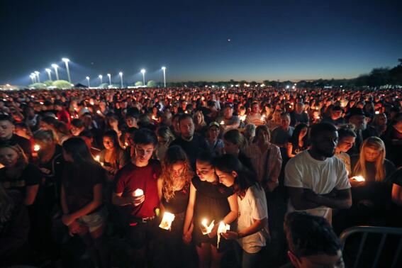 FILE - People attend a candlelight vigil for the victims of the Wednesday shooting at Marjory Stoneman Douglas High School, in Parkland, Fla., Thursday, Feb. 15, 2018. After a gunman murdered 14 students and three staff members at Parkland’s Marjory Stoneman Douglas High School, their families were left with a burning question: How do we go on with our lives while honoring our loved one’s memory? (AP Photo/Gerald Herbert, File)