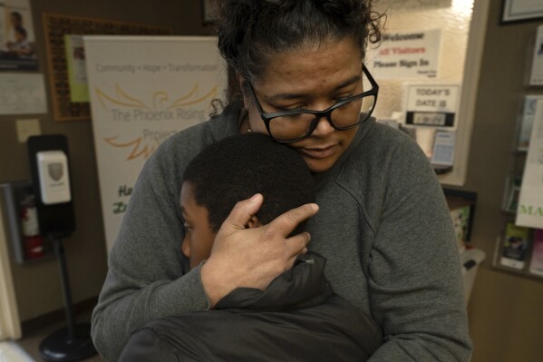 Tiffany McCarter, executive director of the African American Family and Cultural Center, hugs Josiah Banks before he leaves the center for the day in Oroville, Calif., Feb. 8, 2024. A measure aimed at transforming how California spends money on mental health will go before voters in March as the state continues to grapple an unabated homelessness crisis. McCarter fears the 14-year-old facility with a mission of breaking the cycle of trauma in the Black community, might have to close if it loses mental health funding from the Butte County.(AP Photo/Rich Pedroncelli)