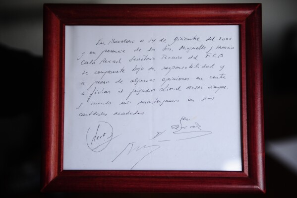 FILE - A framed copy of the napkin linking the 13-year-old Lionel Messi to FC Barcelona is seen in Barcelona, Spain on Jan. 5, 2012. Messi's record-breaking career with Barcelona started with a contract written on a napkin. It's up for auction with a starting price of 300,000 pounds ($379,000). British auction house Bonhams is selling the napkin in an online auction from March 18-27 on behalf of Horacio Gaggioli, an agent from Argentina who was part of the deal. The writing on napkin reads: 
