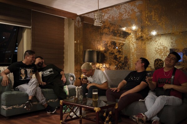 Guillermo Barraza, left, his partner Francisco, and their friends, gather for a watch party for the first broadcast of Barraza's news program "La Verdrag" on Canal Once, at his home in Mexico City, Thursday, Oct. 12, 2023. After watching, Barraza flicked through rows of hate comments flooding Canal Once’s social media, something that would only continue to grow with each broadcast. (AP Photo/Aurea Del Rosario)