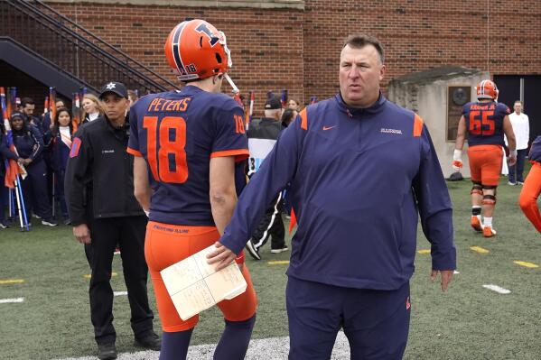 FILE - Illinois head coach Bret Bielema, right, watches his players walk off the field including quarterback Brandon Peters (18) after the team's 20-14 loss to Rutgers in an NCAA college football game Saturday, Oct. 30, 2021, in Champaign, Ill. (Bielema has tested positive for COVID-19 and will miss his team's game at No. 18 Iowa on Saturday. Bielema said Tuesday, Nov. 16, 2021, he was tested for the virus Monday night after developing mild symptoms during the day.AP Photo/Charles Rex Arbogast, File)