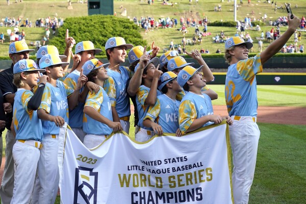 El Segundo, Calif.'s Jaxon Kalish (22) takes a photo with the team and the championship banner after they defeated Needville, Texas, in the United States Championship baseball game at the Little League World Series tournament in South Williamsport, Pa., Saturday, Aug. 26, 2023. (AP Photo/Tom E. Puskar)