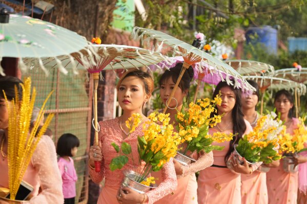 People carrying flowers walk during a processional parade as part of a celebration of a novitiation or “Shinbyu,” ceremony, Saturday, March 15, 2025, at Hlegu township, outside of Yangon, Myanmar. (AP Photo/Thein Zaw)