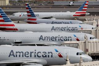 FILE - In this March 25, 2020, file photo, American Airlines jets sit idly at their gates as a jet arrives at Sky Harbor International Airport in Phoenix. American Airlines is telling 25,000 workers that they could lose their jobs in October because of the sharp drop in air travel during the virus pandemic. The airline said Wednesday, July 15, it was starting new offers of buyouts and partially paid leave, which it hopes will reduce the number of furloughs. (AP Photo/Matt York, File)