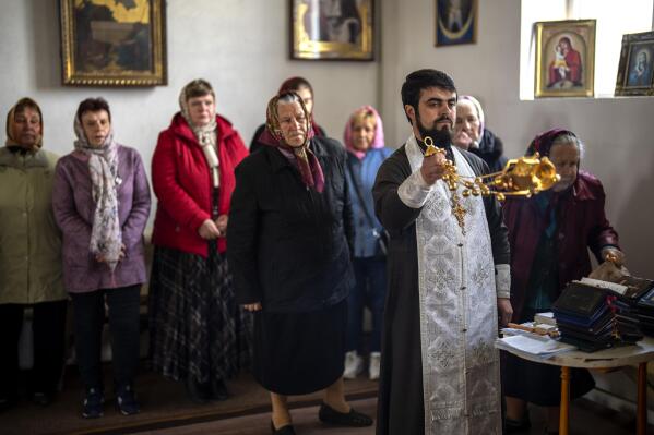 Father Vasyl Bentsa conducts a religious service to commemorate the fallen during the Russian occupation in Zdvyzhivka, Ukraine, on the outskirts of Kyiv, on Saturday, April 30, 2022. (AP Photo/Emilio Morenatti)