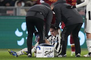 Personal médica asiste a Federico Chiesa, jugador de la Juventus, durante el partido contra la Roma, el domingo 9 de enero de 2022. (AP Foto/Alessandra Tarantino)