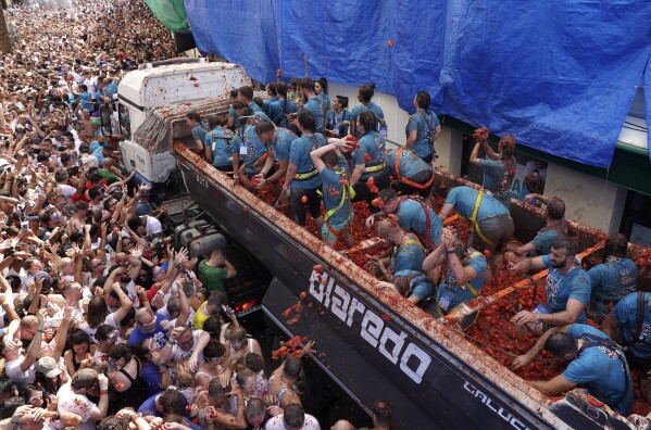 Revellers throw tomatoes at each other during the annual "Tomatina", tomato fight fiesta, in the village of Bunol near Valencia, Spain, Wednesday, Aug. 30, 2023. Thousands gather in this eastern Spanish town for the annual street tomato battle that leaves the streets and participants drenched in red pulp from 120,000 kilos of tomatoes. (AP Photo/Alberto Saiz)