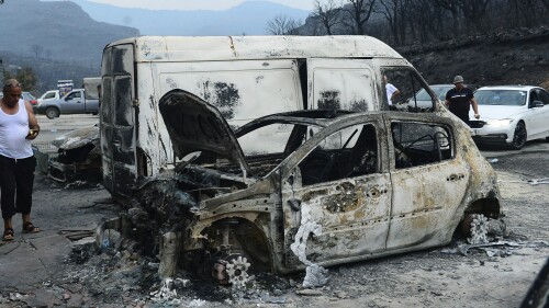 People inspect burnt vehicles after raging wildfires, in Bouira, 100 km from Algiers, Algeria, Monday, July 24, 2023. Wildfires raging across Algeria have killed at least 25 people, including soldiers trying to get the flames under control in the face of high winds and scorching summer temperatures, government ministries said Monday. (AP Photo)