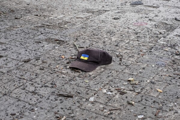 A cap with a Ukrainian flag lies on the ground after a Russian missile strike on Sumy, Ukraine, Sunday April 13, 2025. (AP Photo/Volodymyr Hordiienko)